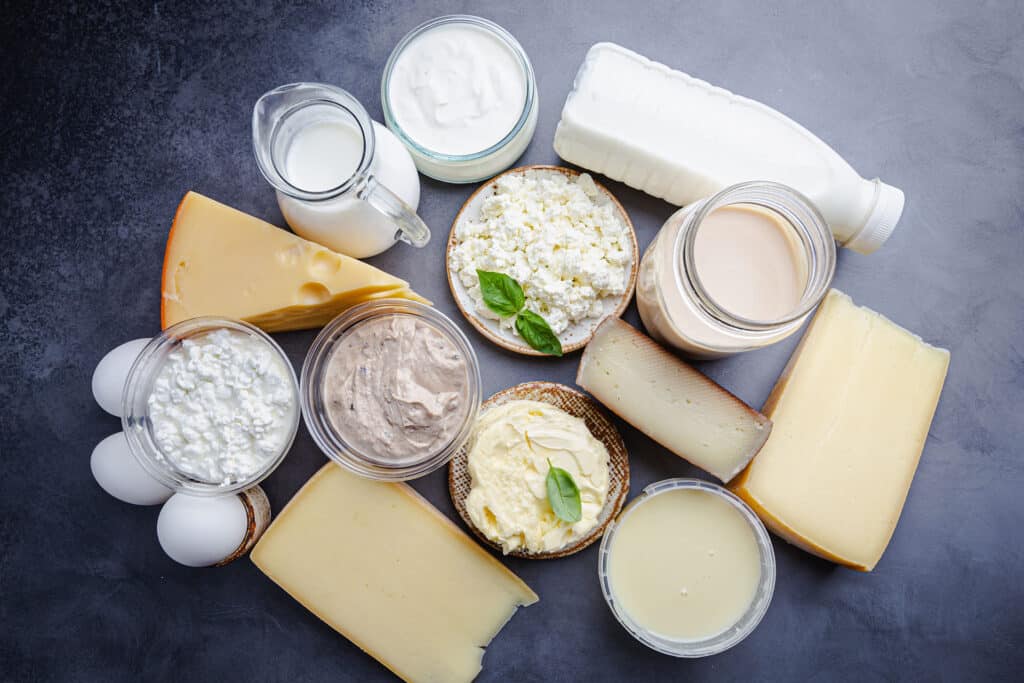 Fresh dairy products, milk, cottage cheese, eggs, yogurt, sour cream and butter on black background, top view